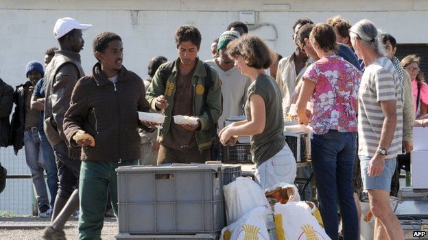 Members of an NGO distribute food to migrants in Calais (5 August 2014)
