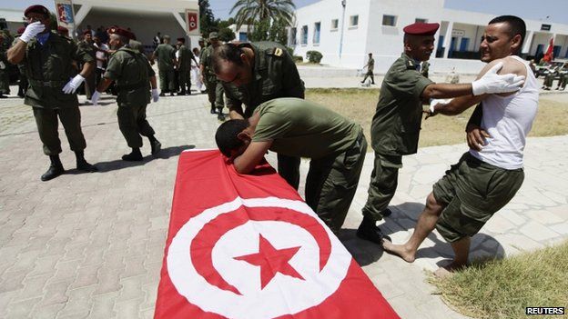 A wounded Tunisian soldier mourns the death of his colleague during his funeral
