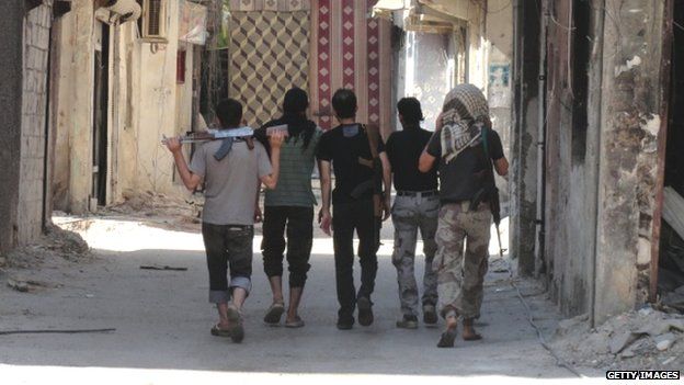 Rebel fighters walk holding their weapons to a position on a front-line in a rebel-held suburb of Damascus