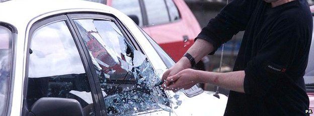 A car window being smashed by a police officer during a car crime demonstration
