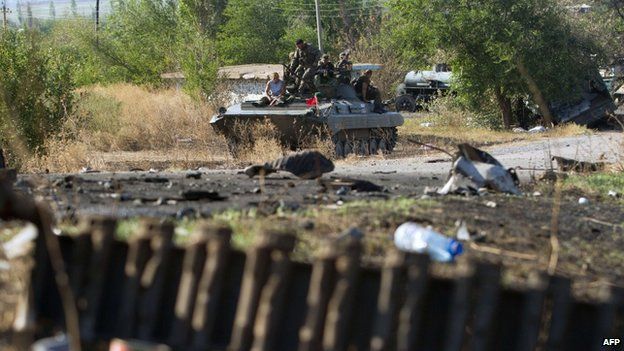 Pro-Russian separatists sit on top an armoured personnel carrier near a destroyed tank on a road in the village of Novokaterinovka, some 50km southeast of Donetsk
