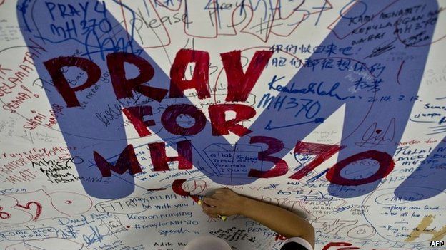 This file photo taken on 14 March 2014 shows a Malaysia Airlines employee writing a message expressing prayers and well-wishes for passengers onboard missing Malaysia Airlines (MAS) flight MH370 at Kuala Lumpur International Airport