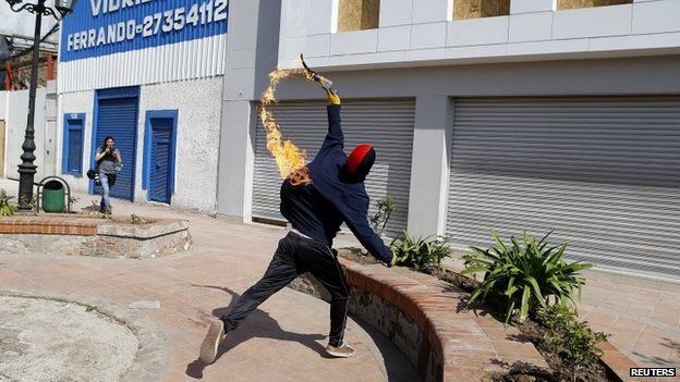 A demonstrator throws a Molotov cocktail towards a bank branch during a protest in Santiago on 7 September