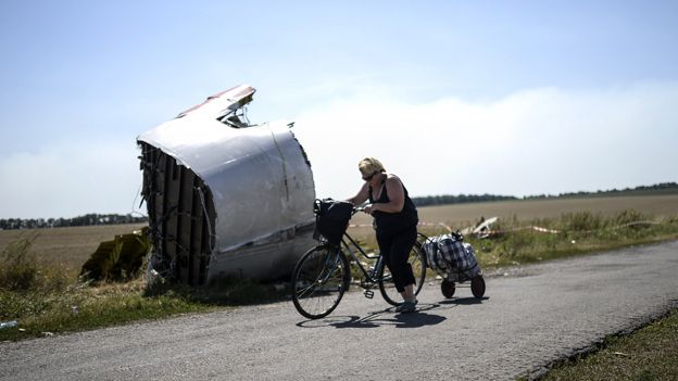 Woman cycles past wreckage of MH17 in a field in Ukraine