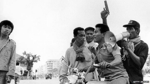 A Khmer Rouge guerrilla soldier holding a gun rides a motorcycle while he and his fellow comrade enter Phnom Penh on 17 April 1975