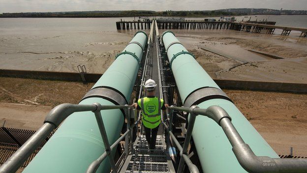 Worker walks between pipes at Thames Gateway Water Treatment Works