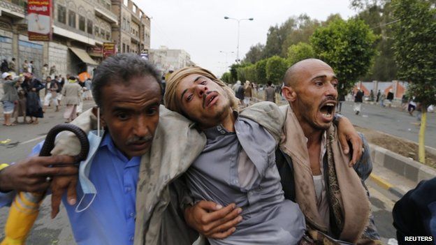 Shia Houthi protesters carry a fellow protester suffering from tear gas inhalation during clashes with riot police along the main road leading to the airport in Sanaa (7 September 2014)