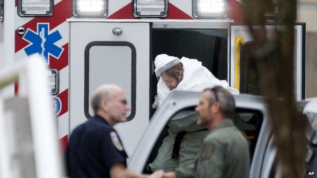A person wearing a haz-mat suit steps out of an ambulance as an Ebola patient arrives for treatment in Atlanta (9 September 2014)