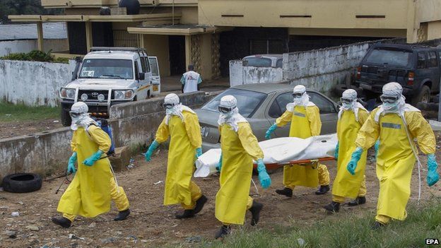 Liberian health care workers on an Ebola burial team collect the body of an Ebola victim at a motor vehicle garage in Paynesville on the outskirts of Monrovia, Liberia (9 September 2014)