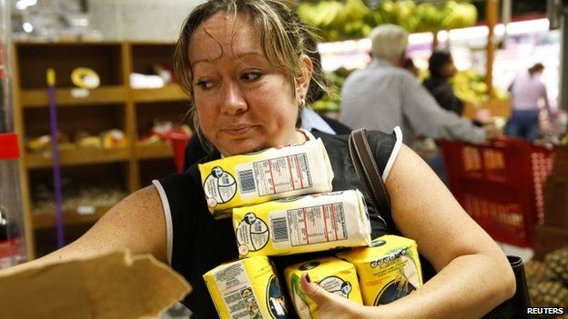 A woman grabs packages of corn flour at a supermarket in Caracas (21 August 2014)