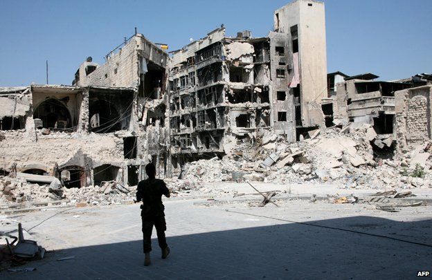 A soldier from the Syrian government forces looks at severely damaged buildings in the northern Syrian city of Aleppo on September 3, 2014.