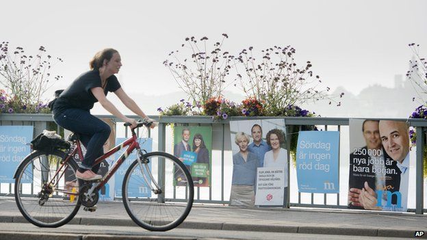 A cyclist in Stockholm passes election posters for the two largest parties in Sweden