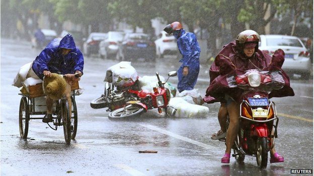 A motorcycle (centre) falls on the street as residents ride their vehicles against strong wind and heavy rainfall under the influence of Typhoon Kalmaegi, in Haikou, Hainan province 16 September 2014.