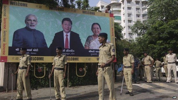 Indian policemen stand next to a welcome hoarding being erected ahead of an anticipated visit by Chinese President Xi Jinping as they review security arrangements in Ahmadabad, India, Monday, Sept. 15, 2014