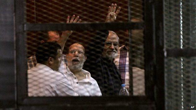 File photo: Senior Muslim brotherhood leader Essam el-Erian, centre left, and their spiritual leader Mohammed Badie, centre right, appear in a courtroom cage accompanied by a policeman, in Cairo, Egypt, 31 August 2014