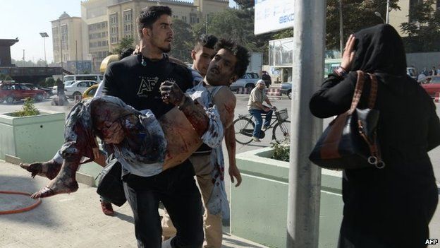 Afghan national rugby team captain Sayed Mustafa Sadat (left), 27, runs with a victim of a suicide attack in his arms to a hospital in Kabul on 16 September 2014