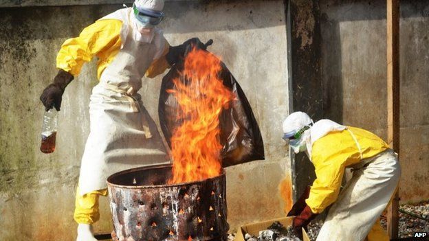 Health workers burn used protection gear at the NGO Medecins Sans Frontieres (Doctors Without Borders) centre in Conakry, Guinea, 13 September 2014