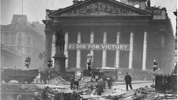 Soldiers help to clear the debris of Bank Underground Station, in front of The Royal Exchange, London, the morning after receiving a direct hit during the Blitz. The slogan 'Dig For Victory' adorns the Exchange. Jan 14 1941