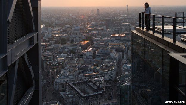 A woman looks out at the London skyline from an upper floor of a newly constructed skyscraper, The Leadenhall Building, as the sun sets on September 9, 2014