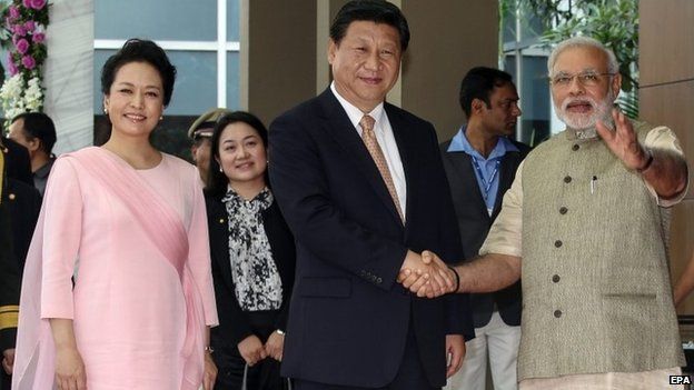 Chinese President Xi Jinping (C) accompanied with his wife Peng Liyuan (L), and Indian Prime Minister Narendra Modi as the two men shake hands in Ahmedabad, India, 17 September 2014.