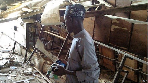 A student looks over at the damage to a lecture hall at the Federal College of Education in the northern Nigerian city of Kano