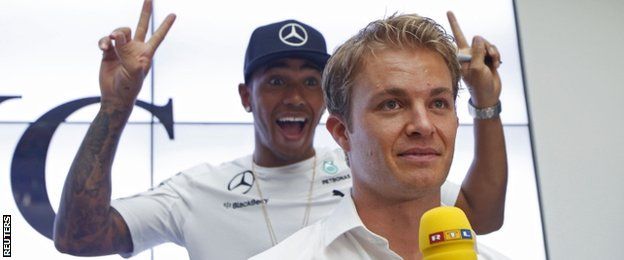 Mercedes Formula One driver Lewis Hamilton of Britain gestures to fans as he passes team-mate Nico Rosberg of Germany