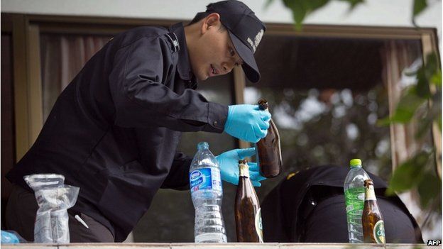 A police investigator examines a beer bottle