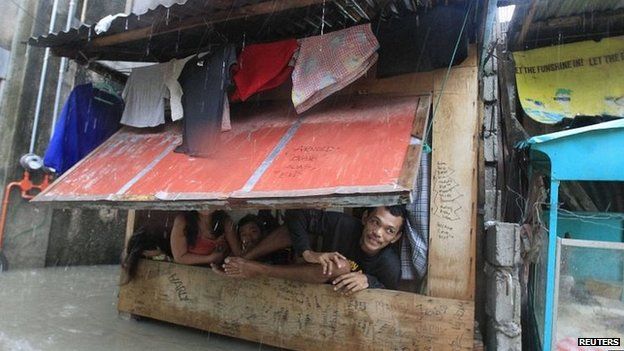 Manila residents shelter in a shanty dwelling amid floodwater (19 Sept 2014)