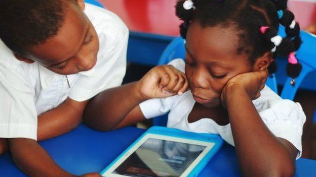Young pupils looking at the Qelasy tablet in the Ivory Coast
