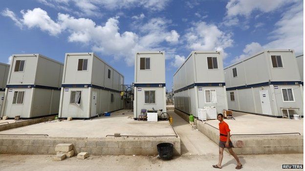 A migrant walks past container houses at the Hal Far Tent Village open centre outside Valletta 2 September 2014