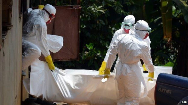 Liberian Red Cross health workers, wearing protective suits, carry the body of a 18-old-month baby, a victim of the Ebola virus in a district of Monrovia, 12 September 2014