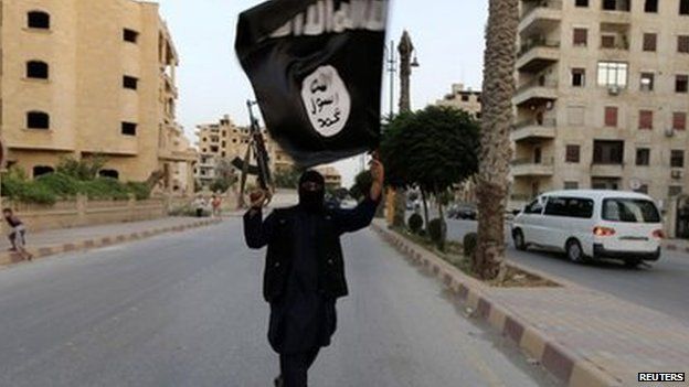 Islamic State fighter waves an IS flag in Raqqa, Syria - June 29, 2014