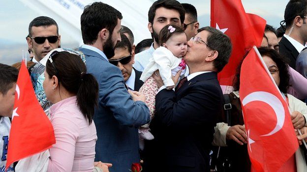 Turkish Prime Minister Ahmet Davutoglu celebrates with freed hostages in Ankara.