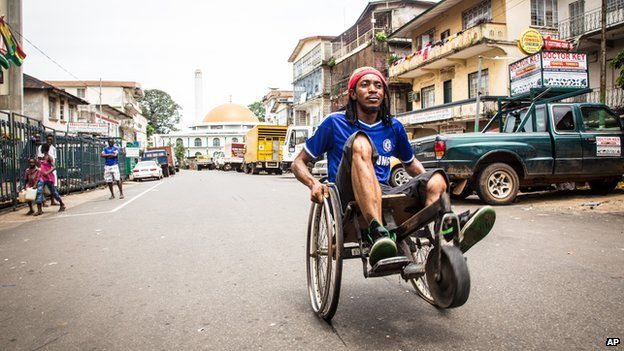 A man travels along a street in his wheelchair during a three-day lockdown to prevent the spread of the Ebola virus in Freetown, Sierra Leone, Sunday, Sept. 21, 2014