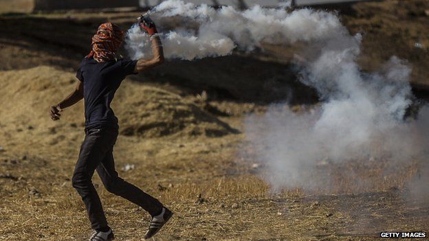 A Kurdish protestor throws a gas canister back to Turkish soldiers near the Syrian border after Turkish authorities temporarily closed the border near the south-eastern town of Suruc in Sanliurfa province, on 22 September 2014.