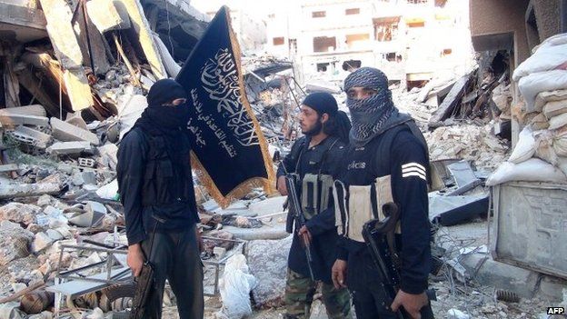 Al-Nusra Front members stand beside wrecked buildings in the Yarmouk Palestinian refugee camp in the south of Damascus (24 September 2014)