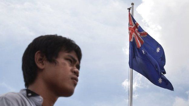 A Cambodian man stands near an Australian flag along the riverside on 13 August 2014 in Phnom Penh, Cambodia.