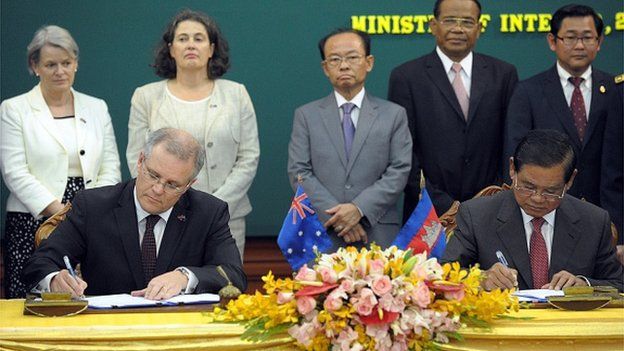 Cambodian minister of Interior Sar Kheng (R) signs documents next to Australian Immigration Minister Scott Morrison (L) during a signing ceremony
