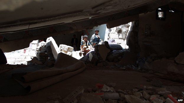 Yemeni children sit amid the debris of their house