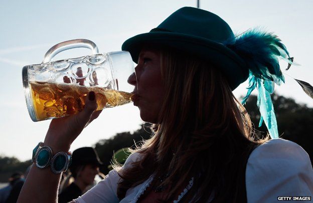 Woman in silhouette drinking from litre jug of beer at Oktoberfest