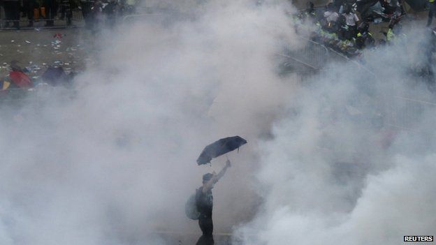 A protester walks in tear gas fired by riot policemen after thousands of protesters blocking the main street to the financial district outside the government HQ in Hong Kong on 28 September 2014.
