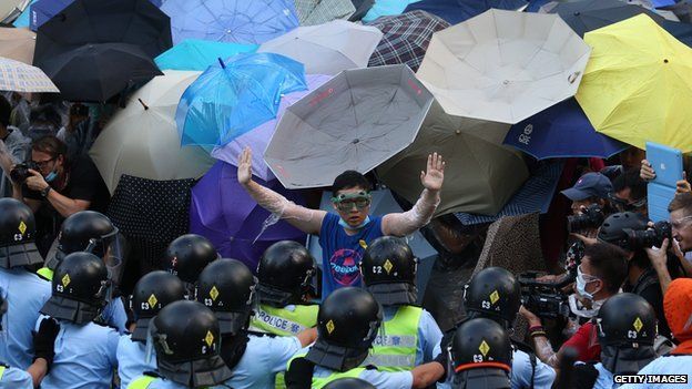 A pro-democracy demonstrator (C) gestures in front of a police line near the Hong Kong government headquarters on 28 September 2014.