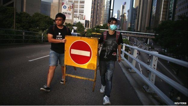 Protesters move a traffic sign as they try to block a street near the government headquarters in Hong Kong - 29 September 2014