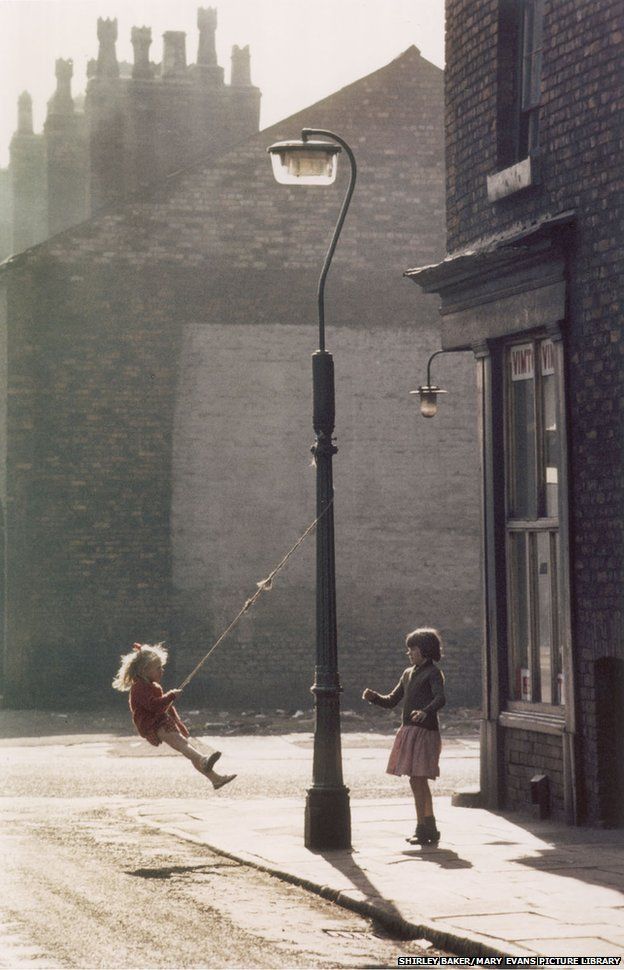 Two girls swing on a lamppost, Manchester 1965