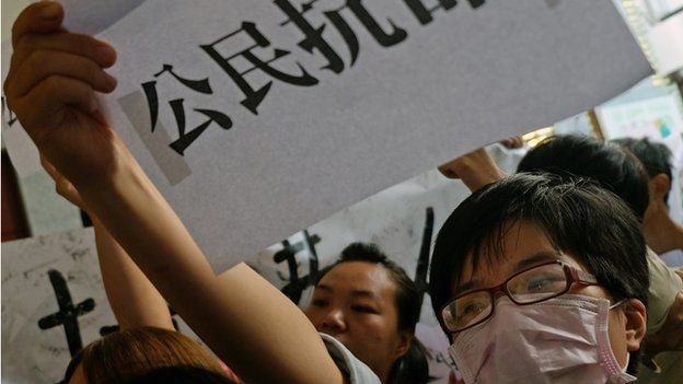 A student protester displays a placard reading "citizen disobey orders" during a protest at the lobby of the Hong Kong office in Taipei on 29 September 2014