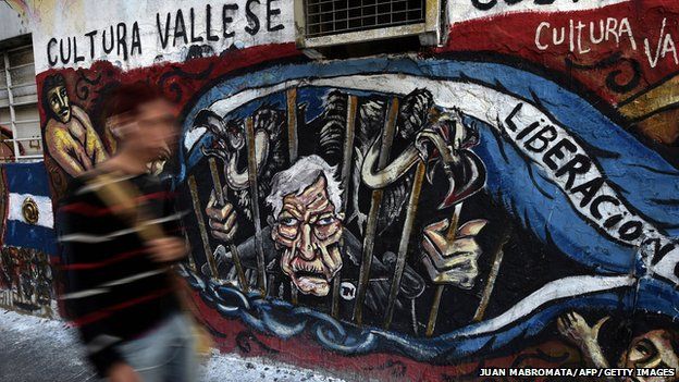 A man walks by a grafitti depicting US' Judge Thomas Griesa and vultures behind bars outside the National Congress in Buenos Aires