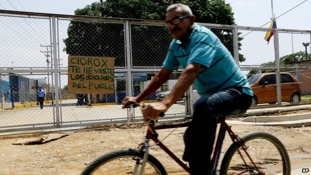 A man rides his bicycle past the main gate of a Clorox factory in Guacara, Venezuela on 27 September, 2014
