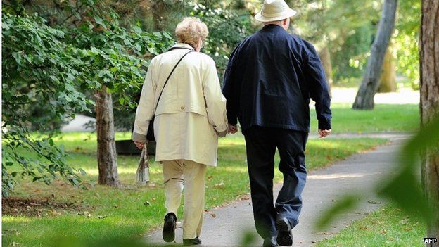 An older couple walk holding hands
