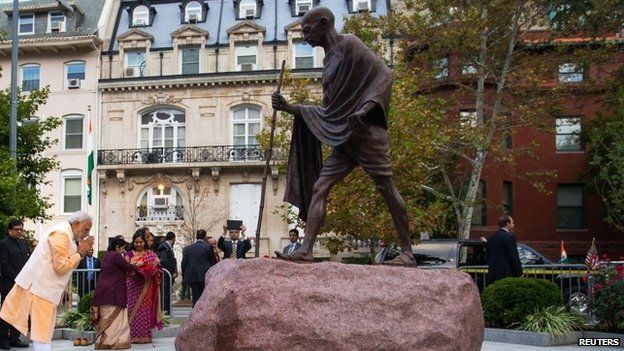 India's Prime Minister Narendra Modi bows his head after scattering flower petals at the feet of the Mahatma Gandhi Statue outside the Indian Embassy in Washington 30 September 2014