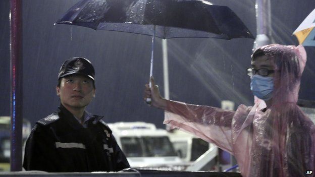 A young pro-democracy demonstrator holds an umbrella for a police officer during a demonstration in Hong Kong on 30 September 2014.